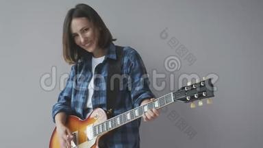 幸福美丽的女人用电吉他演奏<strong>摇滚</strong>和蓝调歌曲，穿着蓝色休闲衬衫微笑和笑。 <strong>摇滚</strong>吉他p