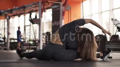 一个运动苗条的女人肌肉背部的足，她练习健身，坐在一个现代的运动健身房。 她是