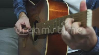男人用手弹吉他。 手指在吉他弦上弹奏。 关门