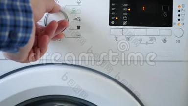 男人使用洗衣机设定程序温度水平和推动启动按钮
