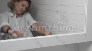 年轻困倦的女人洗脸，在浴室用毛巾擦拭