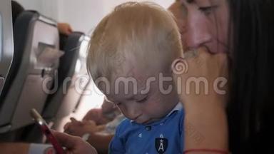 年轻的妈妈和小儿子坐在飞机上打电话。<strong>旅游</strong>、<strong>旅游</strong>和家庭概念。