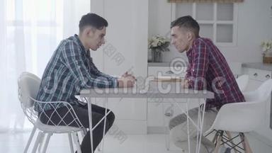 两个成年白种人双胞胎<strong>兄弟</strong>坐在桌子前交谈。 友好的<strong>兄弟</strong>姐妹