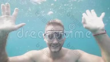 快乐的年轻人在水下挥手微笑，看着相机度假。