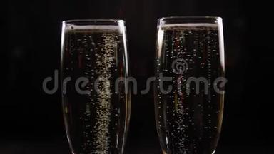 特写<strong>两杯香槟</strong>，黑色背景上有气泡。 博克。
