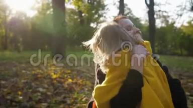 无忧无虑的孩子，快乐的微笑的女孩子在秋天的公园散步时紧紧地拥抱她慈爱的母亲