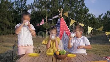 孩子们<strong>解渴</strong>，快乐的孩子们在森林里野餐时<strong>喝</strong>着一杯牛奶，在度假的背景下