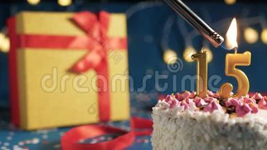 白色生日蛋糕数字15金蜡烛点燃打火机，蓝色背景灯和礼品黄盒子捆绑