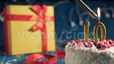 白色生日蛋糕数字10金蜡烛点燃打火机，蓝色背景灯和礼品黄盒子<strong>捆绑</strong>