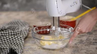 女人用搅拌机搅拌黄油和糖。 在碗里搅拌原料。