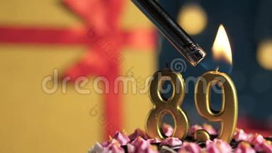 生日蛋糕89号金色蜡烛用打火机点燃，蓝色背景礼品黄色盒子用红丝带绑好