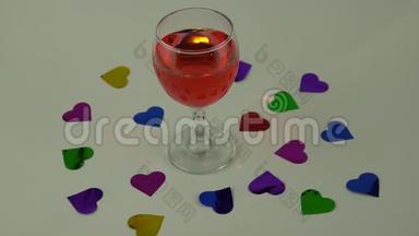 一杯白色背景的红酒。 心形纸屑的散射。 情人节庆祝活动`概念