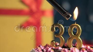 生日蛋糕38号金色蜡烛用打火机点燃，蓝色背景礼品黄色盒子用红丝带系好