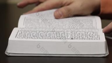 桌子上放着一本公开的圣经。 一个人慢慢地翻页寻找想要的<strong>章节</strong>。 特写镜头