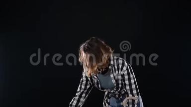 一个年轻女人用扫帚在铲子里扫垃圾的裁剪镜头。 清洁理念。 孤立于黑色之上