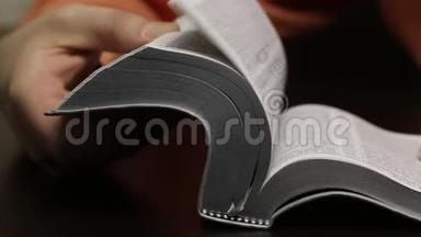 桌子上放着一本公开的圣经。 这个人迅速翻页寻找想要的<strong>章节</strong>。 阅读，引导手指沿着