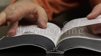桌子上放着一本公开的圣经。 这个人迅速<strong>翻页</strong>寻找想要的章节。 阅读，引导手指沿着