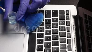 一个戴橡胶手套的人正在清洗他的笔记本电脑。 用<strong>棉签</strong>蘸取清洁剂，清洁笔记本电脑键盘.. 保护