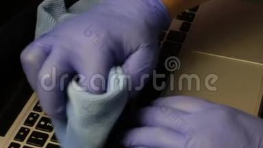 一个戴橡胶手套的人正在清洗他的笔记本<strong>电脑</strong>。 他<strong>用</strong>一张特殊的餐巾纸擦拭笔记本<strong>电脑</strong>键盘。 保护工作设备