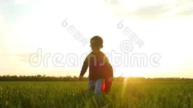 一个穿着超级英雄服装的快乐欢笑的孩子跑过一片<strong>绿色</strong>的田野或草地。 他的脸被<strong>光线</strong>照亮