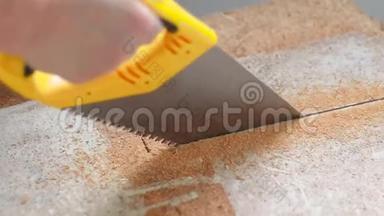 这名工人在家里用手锯锯木护盾. 从刨花板材料中提取的木屑