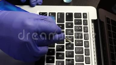 一个戴橡胶手套的人正在清洗他的笔记本电脑。 <strong>棉签</strong>清洁笔记本电脑键盘。 保护工作设备免受