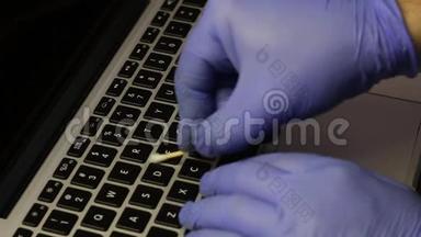 一个戴橡胶手套的人正在清洗他的<strong>笔记本</strong>电脑。 棉签清洁钥匙。 然后他用一个特殊的键盘擦拭<strong>笔记本</strong>电脑键盘