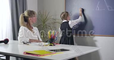 成人白种人教师在黑板上向小女孩口述公式的肖像。 中学教师教学
