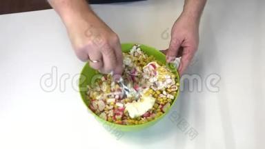 男人做沙拉。 将切碎的蟹条、玉米、北京卷心菜和蛋黄酱混合在容器中