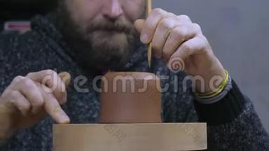 工匠用特殊的木刀从茶壶中取出多余的粘土。 手工泥茶壶宜兴为茶道.. 紫色紫色
