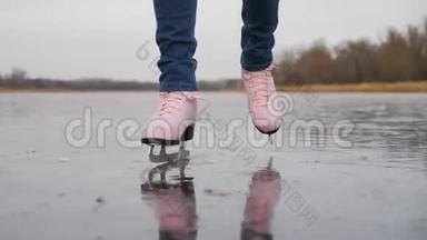 在寒冷的冬日，一位年轻女子在结冰的湖面上滑冰。户外冬季溜冰场上的溜冰者的腿。人
