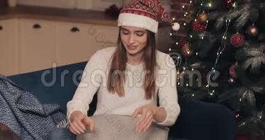 一位穿着毛衣、戴着圣诞帽、坐在沙发上、靠近圣诞树的漂亮女孩最后<strong>敲定</strong>了一个小小的