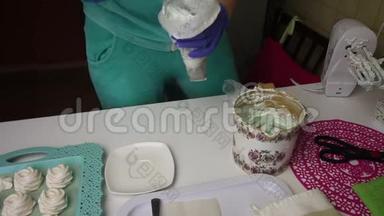 一个女人把棉花糖放进糕点袋里。 在托盘旁边是一个棉花糖，用来稳定