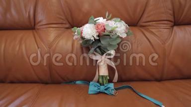漂亮的结婚花束躺在沙发上，戴着结<strong>婚戒</strong>指和新郎的领结