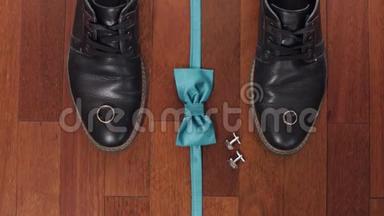 结婚戒指，绿色新郎领结，袖扣和棕色木地板上的鞋子