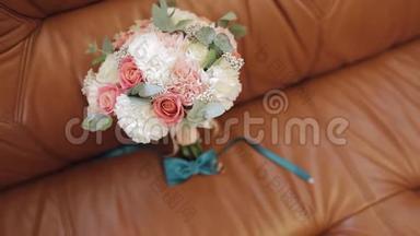 漂亮的结婚花束躺在沙发上，戴着结婚戒指和新郎的领结