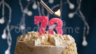 生日蛋糕有73个数字，由较轻的粉红色蜡烛燃烧在蓝色的背景上。 蜡烛被点燃了。 慢动作