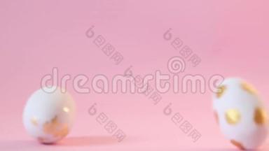 金色粉色白色花纹彩色木蛋随意落在粉色背景上.. 快乐复活节概念，慢动作视频