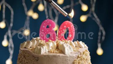 <strong>生日蛋糕</strong>有60个<strong>数字</strong>，由较轻的粉红色蜡烛燃烧在蓝色的背景上。 蜡烛被点燃了。 慢动作
