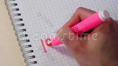 一个女人`手在记事本上用粉红色的记号笔写着“我爱你”和“小心脏”这个词。