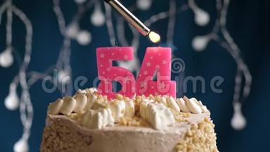 生日蛋糕，54个数字燃烧由较轻的粉红色蜡烛在蓝色的背面。 蜡烛被点燃了。 慢动作
