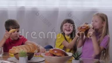快乐的童年，微笑的小朋友坐在桌子旁，在室内的儿童聚会上吃糖果，分享面包，甜蜜的