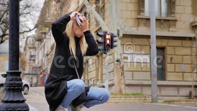 一个年轻的白种人时髦的女人在复古电影相机上拍照。 十字路口道路和红绿灯