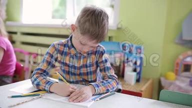 6岁的男孩在学校<strong>课桌</strong>上的一堂课上用笔记本做作业。 学前教育