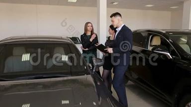 两个女孩和卖家一起去大汽车商店，选择一辆新车。