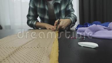 女士裁剪面料与剪刀在裁缝`工作室，肥皂片，安全别针躺在桌子上。 把剪刀剪下布料。 C.C