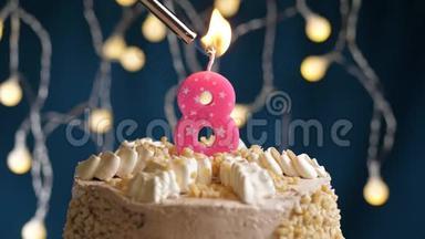 生日蛋糕，8个数字燃烧由较轻的粉红色蜡烛在蓝色的背景。 蜡烛被点燃了。 慢动作和特写
