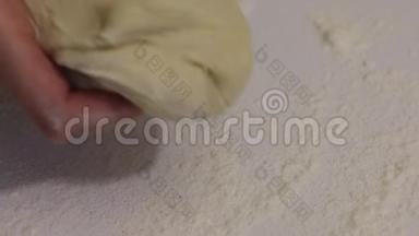 一个女人把面团放在桌面上做朱砂。 桌子上撒上面粉.. 特写镜头