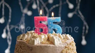 生日蛋糕，蓝色背景上有55个数字的粉红色燃烧蜡烛。 蜡烛吹灭了。 慢速运动和特写镜头