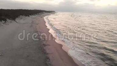 日落后蓝色小时的波罗的海海岸鸟瞰图。 暮光的海岸线带着滚滚的波浪，空旷的海滩